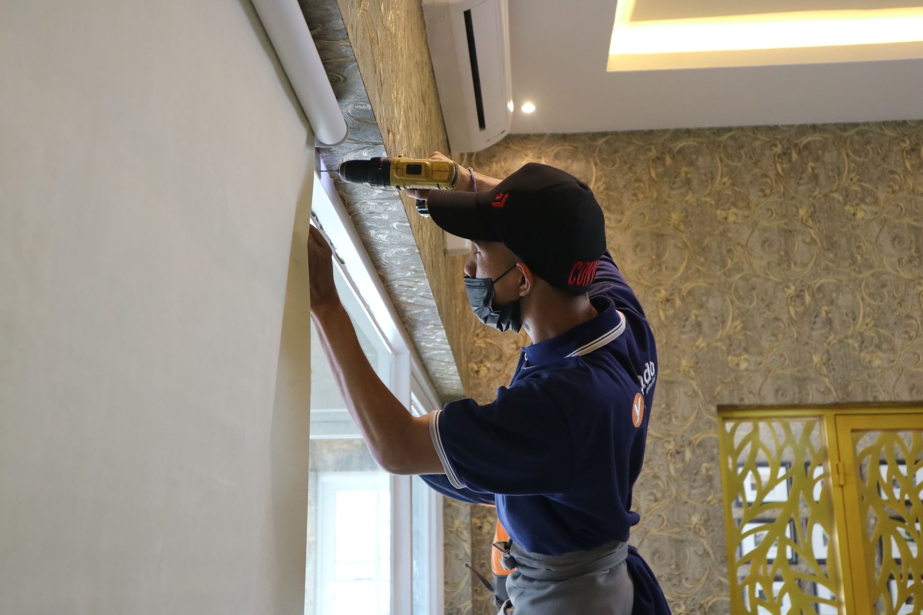 Worker using a drill at a window inside a room